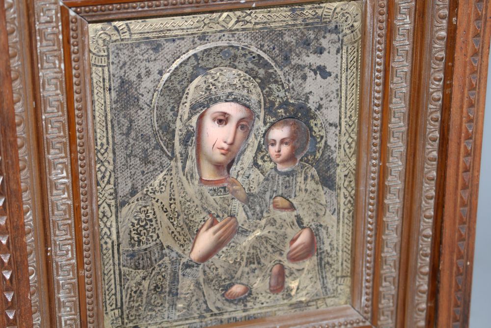 A late 19th century Russian tempera on panel icon, with silver gilt oklad dated 1889, housed in an ornate carved wood casement frame,